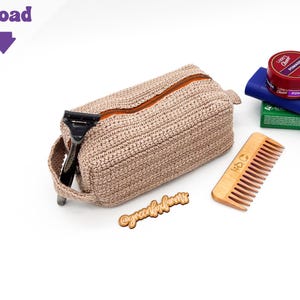 May include: A beige crochet toiletry bag with a brown zipper, a razor, a wooden comb, and a small wooden sign that says "@greenfoxforms". Also included are a jar of pomade and two boxes.