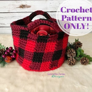May include: Crochet pattern for a red and black buffalo plaid basket with a handle. The basket is filled with red ornaments. The text "Crochet Pattern ONLY!" is in a white circle with a purple outline.