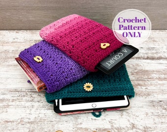 Pode incluir: Três capas de crochê para tablet ou livro em tons de rosa, roxo e verde. Cada capa tem um fecho de botão e está empilhada uma em cima da outra. A capa superior tem um tablet dentro. O texto "Crochet Pattern ONLY" está num círculo acima das capas. O texto "@greenfoxfarms" está abaixo das capas.