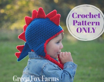 May include: A child wearing a blue and red crocheted dinosaur hat. The hat has a long tail and spikes on top. The text "Crochet Pattern ONLY" is visible in the image.