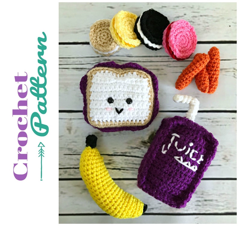 May include: Crochet pattern for a lunchbox with a sandwich, banana, juice box, cookies, and carrots. The sandwich has a cute face.