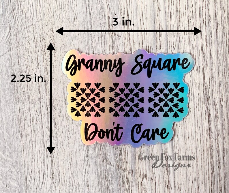 May include: A holographic sticker with the text "Granny Square Don't Care" and a pattern of three granny squares. The sticker is 3 inches wide and 2.25 inches tall. The sticker is from Green Fox Farms Designs.