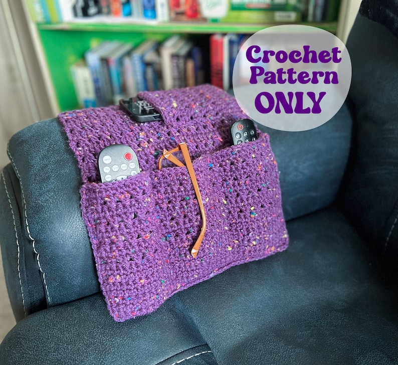 May include: Purple crochet remote control holder with two pockets for remotes and a pocket for glasses. The holder is on a dark gray couch. Crochet Pattern Only.