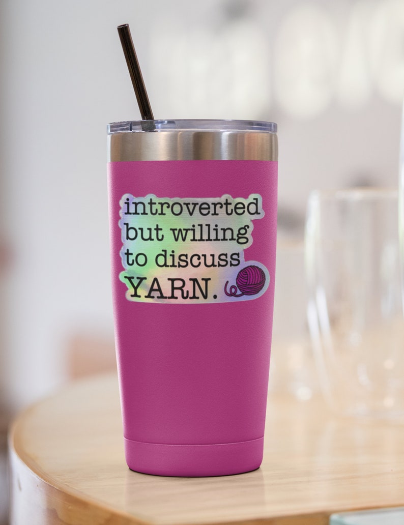 May include: Pink stainless steel tumbler with a black straw and a sticker that says "introverted but willing to discuss YARN." The sticker has a holographic finish and a small yarn ball graphic.