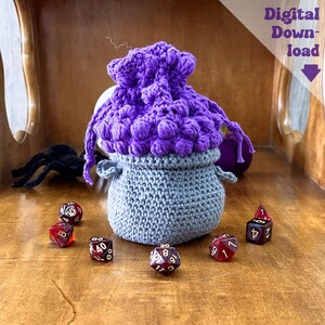 May include: A handmade crochet dice bag in gray and purple. The bag has a textured, rounded shape with a drawstring closure. Several polyhedral dice in red and black are scattered around the bag. The text "Digital Download" is visible.