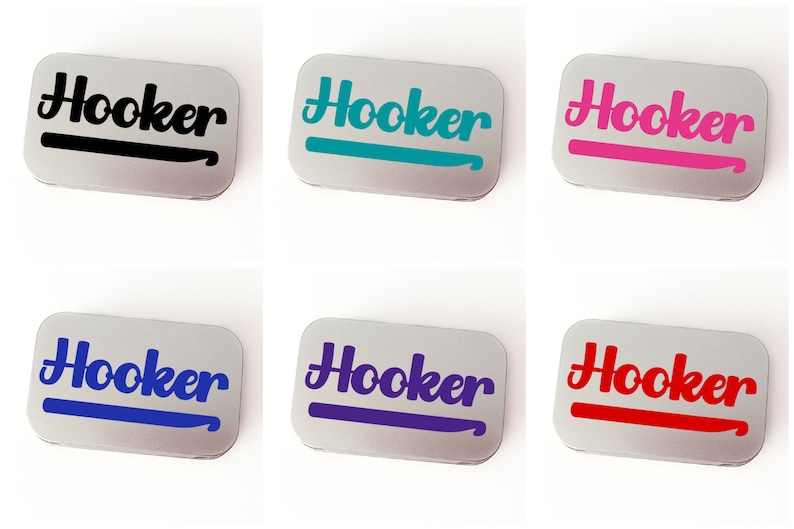 May include: Six small silver tins with the word "Hooker" printed in a stylized font on the front. Each tin has a different colored crochet hook graphic underneath the word. The colors are black, teal, pink, blue, purple, and red.