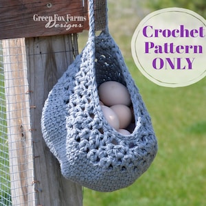 May include: A gray crocheted egg basket hanging on a wooden fence post. The basket is filled with white eggs. The text "Crochet Pattern ONLY" is written in purple on a white circle.