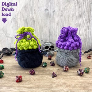 May include: Two crocheted dice bags, one green and black, the other purple and gray, sit on a wooden surface. The bags are surrounded by colorful dice, a metal skull, and a plastic spider. The text "Digital Download" is visible.