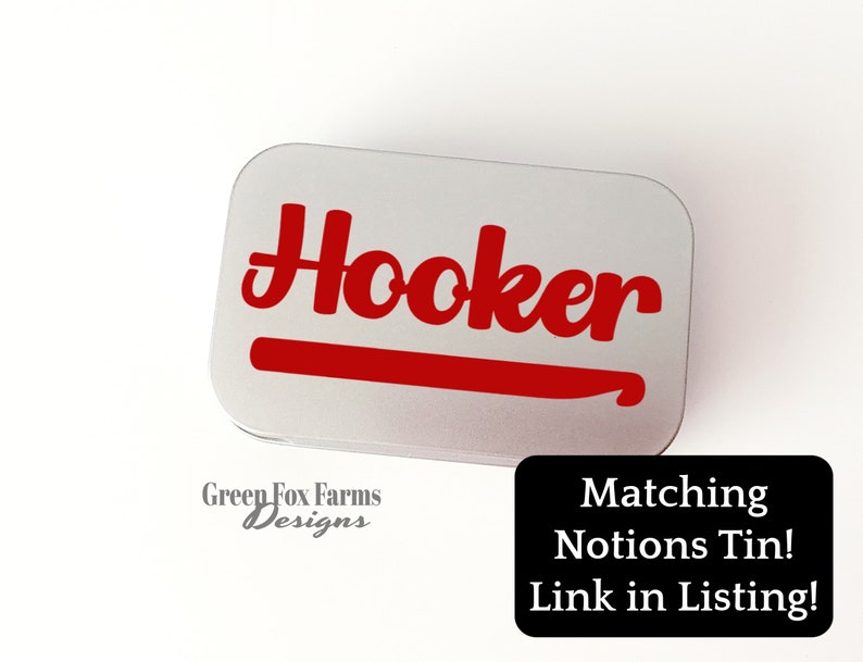 May include: A silver metal tin with the word "Hooker" in red lettering and a red crochet hook graphic. The tin is labelled "Green Fox Farms Designs".