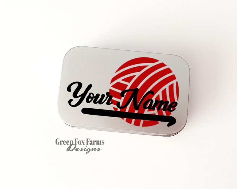 May include: A silver metal tin with a red and white yarn ball and a black crochet hook. The text "Your Name" is written in black cursive lettering on the tin.