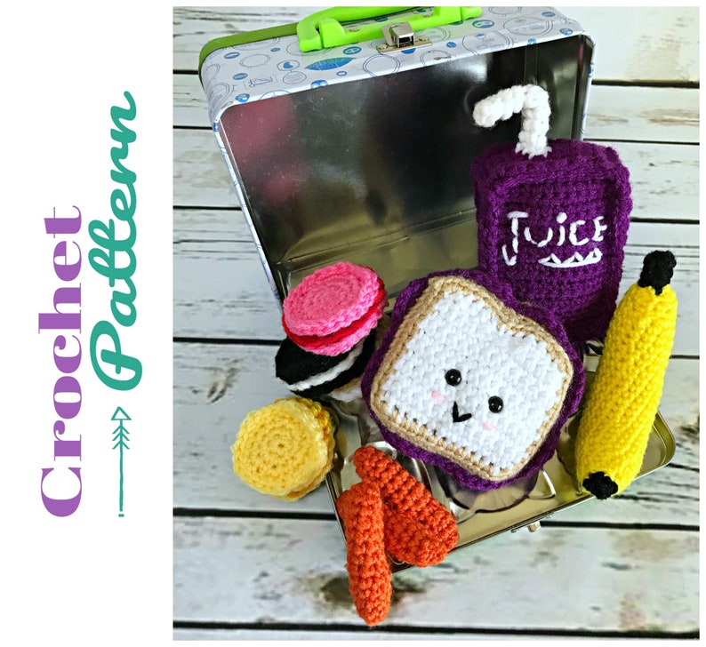 May include: A crocheted lunchbox set with a sandwich, juice box, banana, cookies, and french fries. The lunchbox is a metal tin with a green handle. The crocheted items are all in different colors and have a cute, cartoonish style.