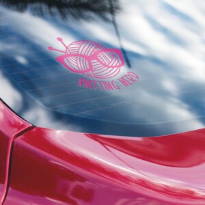May include: Pink car window sticker with a ball of yarn and knitting needles, with the text "Knitting Nerd".