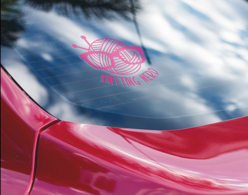 May include: Pink car window sticker with a ball of yarn and knitting needles, with the text "Knitting Nerd".