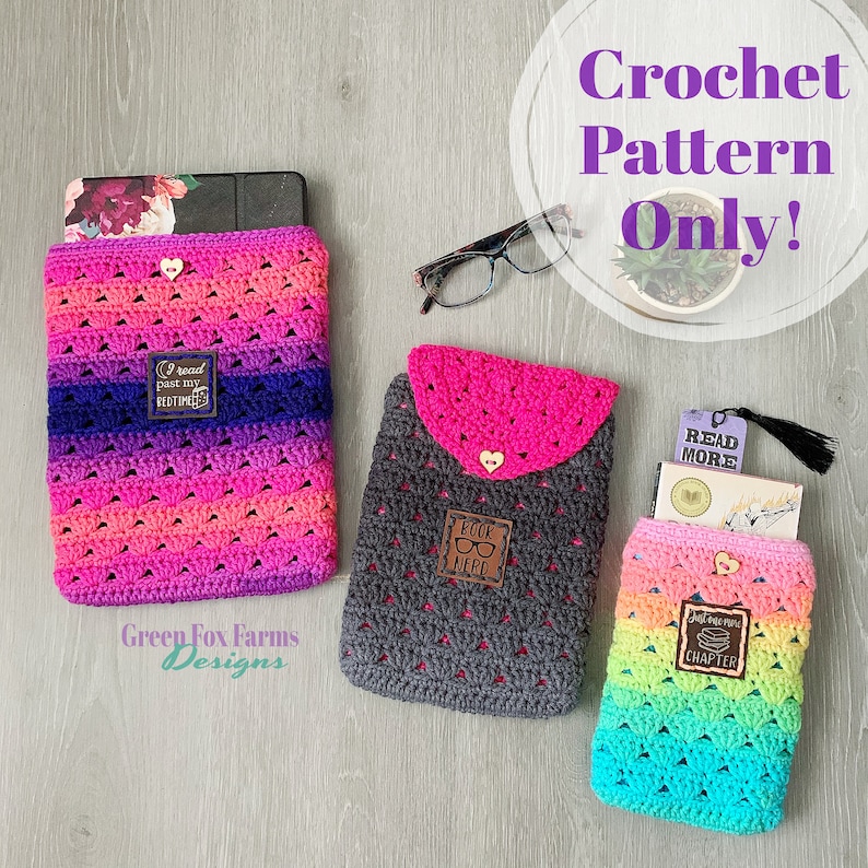 May include: Three crocheted tablet or book covers in different color combinations. The covers are made with a stitch pattern that resembles small triangles. Each cover has a small, decorative heart-shaped button and a leather patch with a different saying. The covers are displayed on a wooden surface. Crochet Pattern Only!