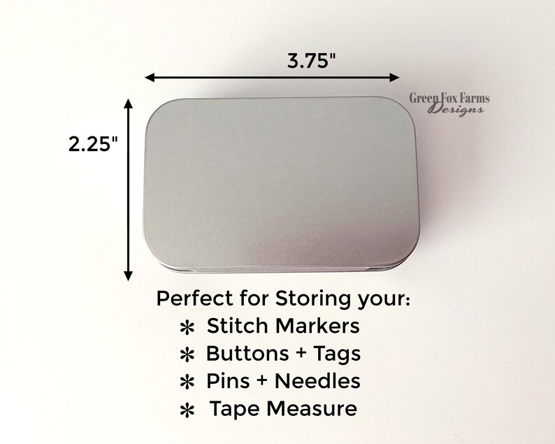 May include: A silver metal tin with a rounded rectangular shape. The tin is 3.75 inches wide and 2.25 inches tall. The text "Perfect for Storing your:" is printed below the tin. The text "* Stitch Markers" is printed below the text "Perfect for Storing your:". The text "* Buttons + Tags" is printed below the text "* Stitch Markers". The text "* Pins + Needles" is printed below the text "* Buttons + Tags". The text "* Tape Measure" is printed below the text "* Pins + Needles". The text "Green Fox Farms Designs" is printed in the top right corner of the image.