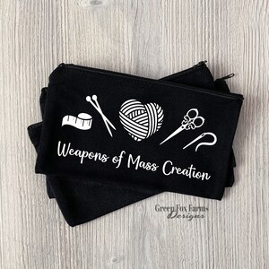 May include: Black zippered pouch with white text that reads "Weapons of Mass Creation". The pouch has a white graphic of yarn, scissors, needles, and a measuring tape.