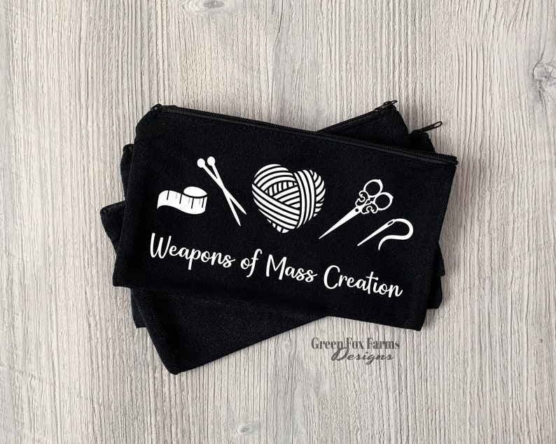 May include: Black zippered pouch with white text that reads "Weapons of Mass Creation". The pouch has a white graphic of yarn, scissors, needles, and a measuring tape.