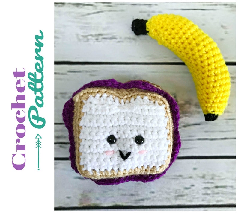 May include: A crocheted peanut butter and jelly sandwich with a smiling face and a crocheted banana. The sandwich is purple, brown, and white. The banana is yellow.