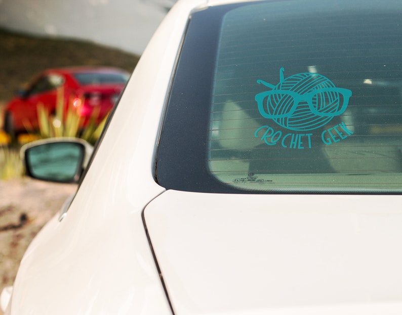 May include: A teal blue car window sticker with a ball of yarn, knitting needles, and glasses. The text "crochet geek" is below the yarn ball.