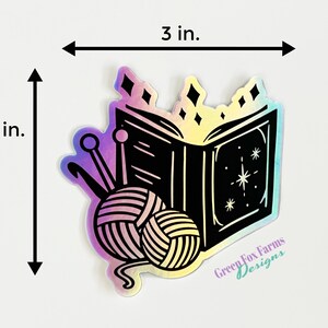 May include: A 3-inch by 3-inch iridescent sticker featuring a black and white illustration of an open book with stars and a ball of yarn with knitting needles. The sticker has the text "Green Fox Farms Designs" at the bottom.