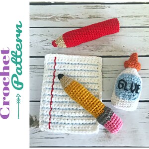May include: Crocheted school supplies including a red pencil, a yellow pencil, a sheet of paper, and a bottle of glue. The glue bottle has the word "GLUE" written on it.