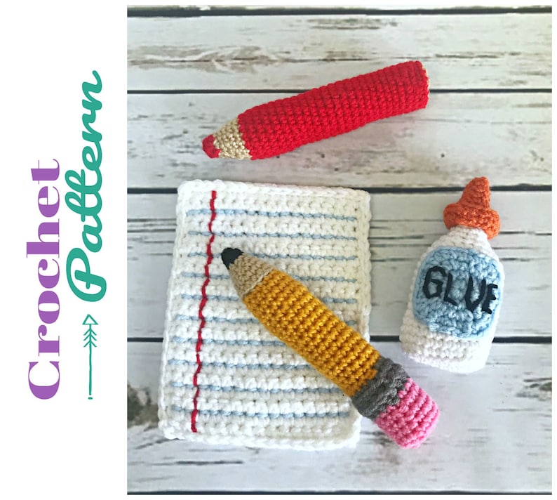 May include: Crocheted school supplies including a red pencil, a yellow pencil, a sheet of paper, and a bottle of glue. The glue bottle has the word "GLUE" written on it.