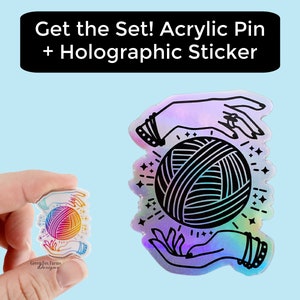 May include: A holographic sticker featuring a pair of hands holding a ball of yarn. The sticker has a rainbow iridescent finish. The text "Get the Set! Acrylic Pin + Holographic Sticker" is displayed above the sticker.
