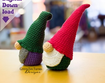 May include: Two handmade crochet gnomes with pointed hats. One gnome has a green hat, a gray and purple body, and a tan nose. The other gnome has a red hat, a white beard, a green body, and a tan nose. The image includes the text "Digital Download" and "Green Fox Farms Designs."