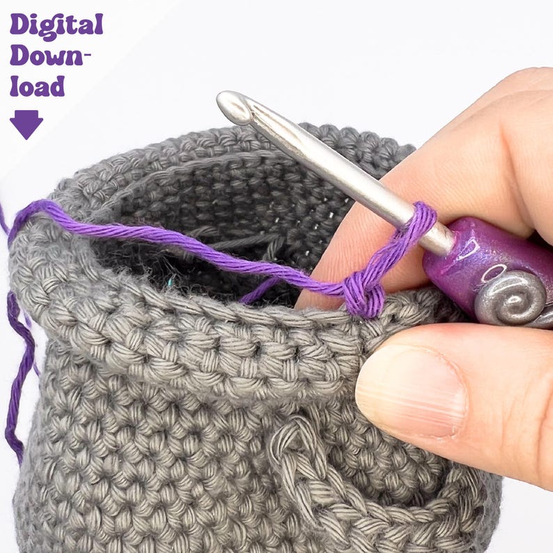 May include: Close-up of a crochet project in progress. A gray crocheted pouch is being worked on with a silver crochet hook and purple yarn. The text "Digital Download" is in the upper left corner.