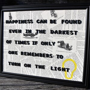 May include: A framed wall art piece featuring a collage of book pages with the black text: HAPPINESS CAN BE FOUND EVEN IN THE DARKEST OF TIMES IF ONLY ONE REMEMBERS TO TURN ON THE LIGHT. A small yellow lightbulb icon is drawn near the bottom right.