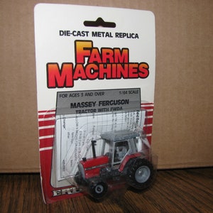 May include: A red and gray die-cast metal replica Massey Ferguson tractor with front wheel drive (FWDA) in a plastic blister pack. The packaging features the words "Farm Machines" in red and white lettering. The tractor is 1/64 scale and is for ages 3 and over.