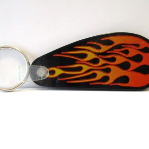 Könnte beinhalten: Schwarzer und orangefarbener Flammen-Schlüsselanhänger mit einem silbernen Schlüsselring.