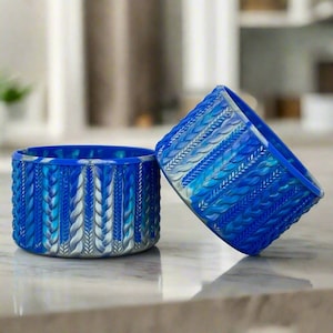May include: Two blue and silver patterned ceramic bowls with a braided design. The bowls are stacked on top of each other.