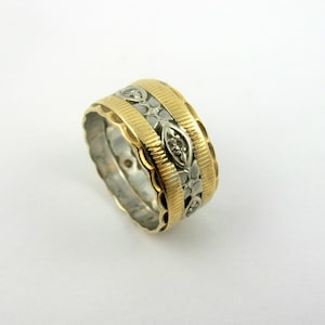 May include: A gold and silver patterned wedding band with a decorative design.