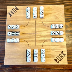 May include: A wooden game board with the word "BURK" printed on each side. The board has four sections with rows of white dice with black dots.