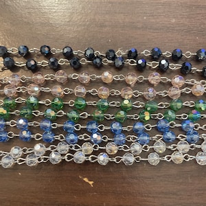 May include: A set of eight beaded necklaces with silver chains. The necklaces feature different colored beads, including black, pink, green, blue, and clear.