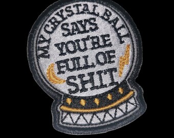 May include: A white embroidered patch shaped like a crystal ball with the text "My Crystal Ball Says You're Full Of Shit" in black with a gold lightning bolt and crescent moon.