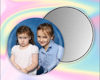 May include: Two young girls, one with a white shirt and the other with a blue shirt, pose for a photo against a blue backdrop.