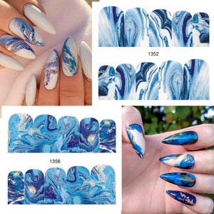 May include: Blue and gold marble nail wraps with a white background. The nail wraps are shown on two sets of fingers. The nail wraps are labeled with the numbers 1352 and 1356.