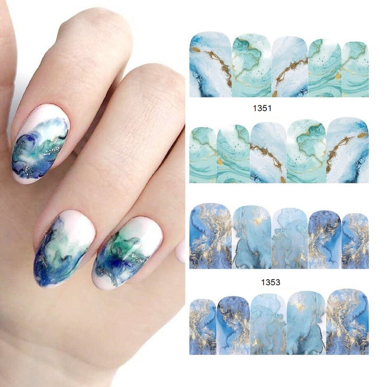 May include: Nail polish wraps with a blue and gold marble design. The wraps are shown on a person's fingernails. The wraps are labeled with the numbers 1351 and 1353.