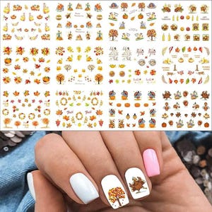 May include: A collection of nail art stickers featuring autumn themes including pumpkins, turkeys, fall leaves, trees, and text such as Happy Thanksgiving and Fall. The stickers are displayed on sheets with various seasonal designs for nail decoration.