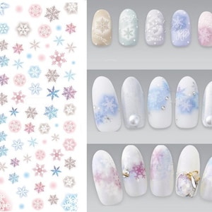 Può includere: Un foglio di adesivi per nail art con disegni di fiocchi di neve in varie tonalità di blu, rosa e bianco. Il foglio include anche alcuni disegni di unghie con fiocchi di neve e glitter.