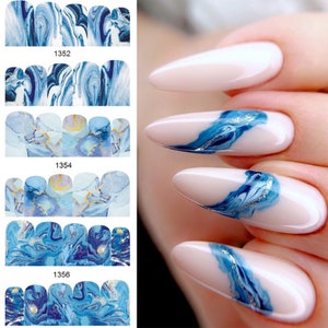 May include: Blue and gold marble nail polish stickers. The stickers are arranged in rows of three, with each row featuring a different design. The stickers are designed to be applied to fingernails.