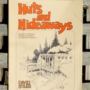 May include: A vintage book cover with an orange title "Huts and Hideaways" and a black and white illustration of a small cabin in the woods. The book is about building woodland shelters and weekend retreats. The author is David Stiles.