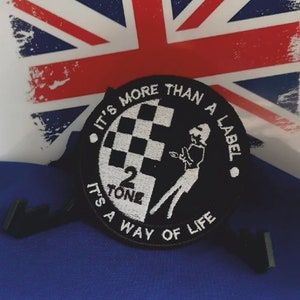 May include: Black and white embroidered patch with the text "It's more than a label. It's a way of life." and the logo "2 Tone" with a checkered pattern and a stylized figure.