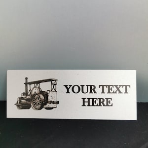 May include: A silver metal plaque with a black and white illustration of a vintage steam engine. The text "YOUR TEXT HERE" is printed below the illustration.