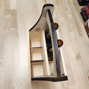 Puede incluir: Cesta de cerveza de madera con asa, dise&ntilde;ada para seis botellas. La cesta est&aacute; hecha de madera clara con detalles en marr&oacute;n oscuro de una t&eacute;cnica de quemado. El asa tiene un dise&ntilde;o curvo para facilitar el transporte. La cesta est&aacute; vac&iacute;a.