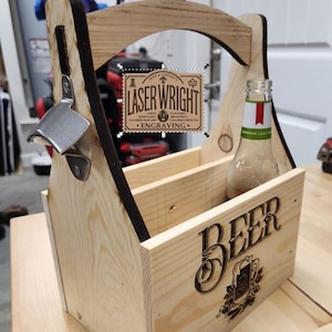 Puede incluir: Un portabotellas de cerveza de madera con un abridor de botellas incorporado. El portabotellas tiene un asa y est&aacute; dise&ntilde;ado para contener varias botellas. La palabra "BEER" est&aacute; grabada en la parte delantera, junto con un emblema decorativo. El portabotellas tambi&eacute;n presenta el texto "LASER WRIGHT ENGRAVING".