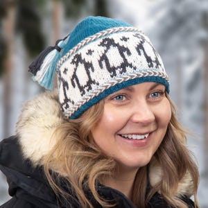 May include: A set of three ceramic mugs with a speckled, cream-colored glaze. Each mug features a different hand-painted design: a blue and green leaf, a yellow flower, and a red berry. The mugs have a simple, modern design.