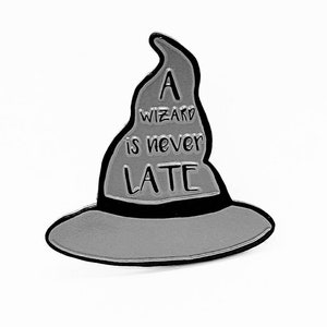 May include: A silver wizard hat pin with a black brim and the text "A wizard is never late" on the front.